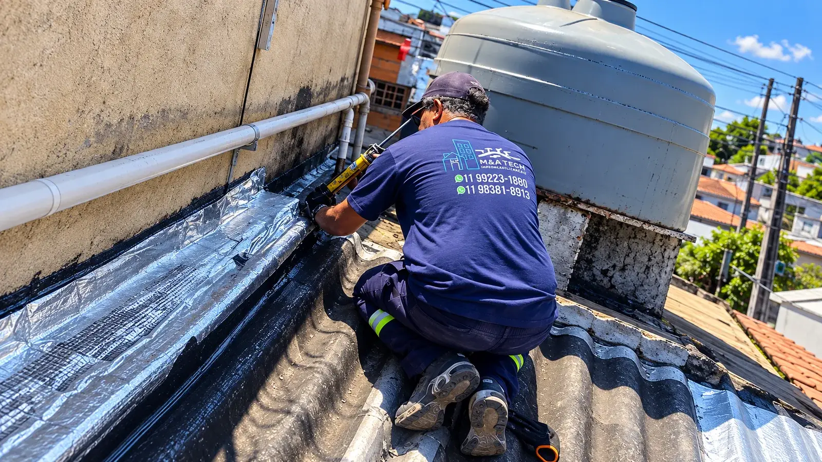 Profissional da MATECH aplicando selante na manta de impermeabilização de uma cobertura, ao lado da caixa-d'água